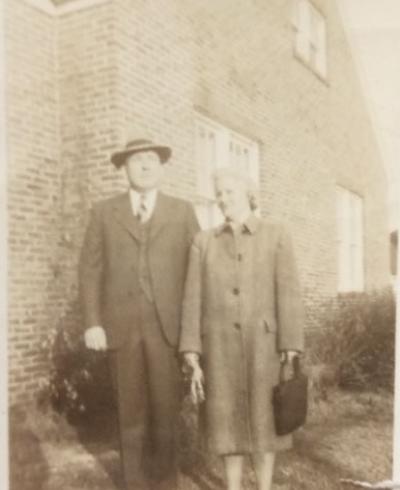 Two people outside the house. Perhaps Bud and Thelma Davis