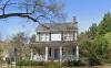 Front of two-story white house with front porch, black shutters, and chimney